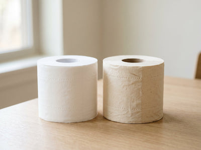 A bright white bleached toilet paper roll beside a natural beige unbleached bamboo roll, showing the colour difference 